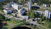 Kuvassa on kesällä ilmasta kuvattu Savonlinnan sairaala-alue, jonka keskellä näkyy korkea tiilipiippu.