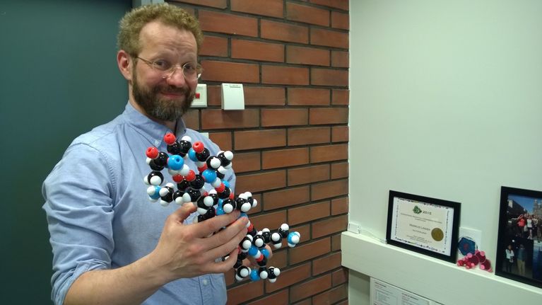 Markus Linder pitää kädessään molekyylimallia.