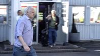 Julian Assange kävelee rakennuksen edustalla.