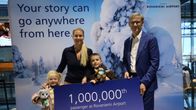 Lentoaseman mainoksen edessä kameraan katsoo lentoaseman johtaja ja vaalea nainen lapsineen.