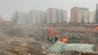 Haiseva jäte on peitetty presulla, kaivuri kaivaa. 