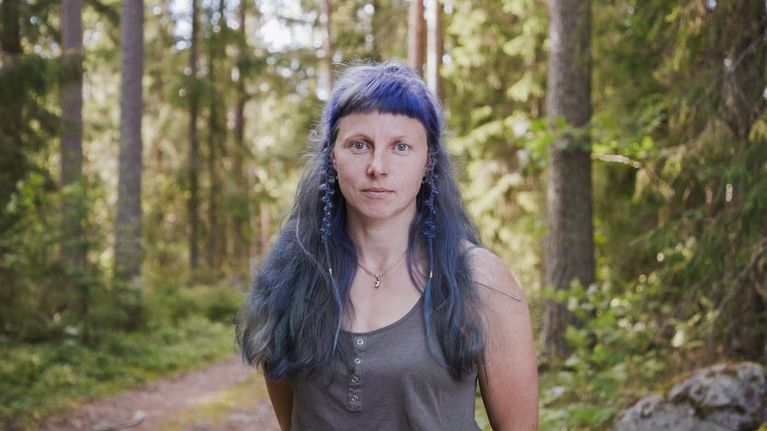 Käsityötaiteilija Elena Bondar lähikuvassa. Taustalla näkyy metsää.