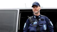 Poliisi seisoo partioauton edessä virkapuvussaan.