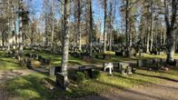 Hautausmaa, jossa riveittäin hautakiviä ja lehtipuita. Joissakin hautakivissä näkyy nimiä ja vuosilukuja.