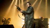 Mies mustassa nahkatakissa eli The KLF:n Bill Drummond lavalla konekivääri kädessä.