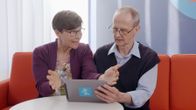 Yli-innokas digiauttaja ja hämmentynyt seniori sihvalla vierekkäin tabletti kädessä. Kuvassa Ylen toimittaja Anu Heikkinen ja Enter-yhdistyksen Ilkka Veuro.