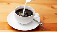 En kopp kaffe som det hälls mjölk i.