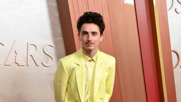 Timothée Chalamet keltaisessa puvussa Oscarien punaisella matolla.