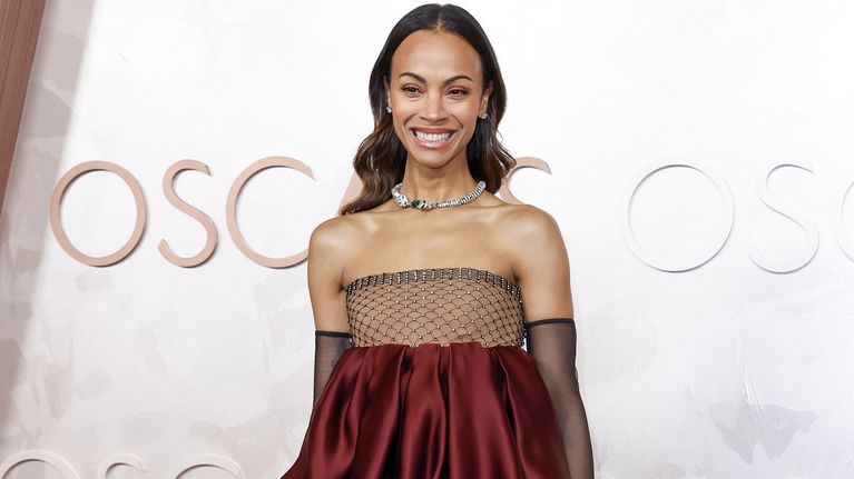 Zoe Saldana viininpunaisessa iltapuvussa, joka rypyttyy kahdeksi pussimaisesti rintojen alapuolelta vyötärölle.