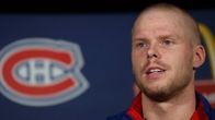 Lyhythiuksinen Saku Koivu lähikuvassa. Kuvassa näkyy Montreal Canadiens -logolla varustettu tausta.