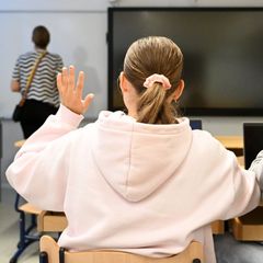 Photo shows two teenagers sitting in a school classroom.