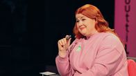 Ani Kellomäki istuu studiossa tuolilla, mikrofoni kädessään.