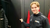 Jääkiekkojoukkueen nuori pelaaja avaamassa pukuhuoneen oveaan.