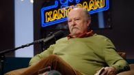 Näyttelijä Jarmo Koski istuu Gogin kantabaari -studion penkillä.