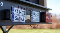 Peräkärrysaunan peräluukussa rekisterikyltit KAJ-123 ja SAUNA.
