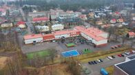 Bild av en grundskola omgiven av bostadshus och natur.