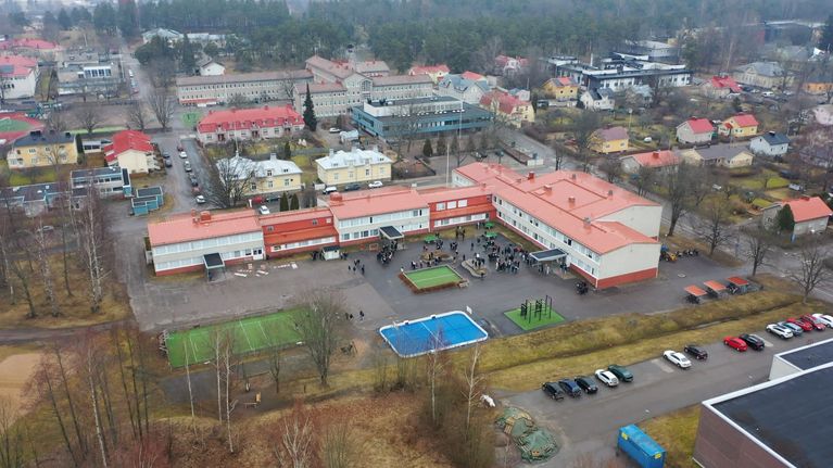 Bild av en grundskola omgiven av bostadshus och natur.