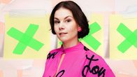 Psykoterapeutti Emilia Kujala puolikuvassa pinkki paita päällään. Hänen takanaan on kolme post it -lappua, joissa on vihreät raksit. 