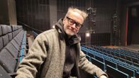 Näyttelijä Jorma Tommila istuu tyhjässä teatterikatsomossa ja hymyilee