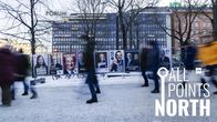 People walking past an election candidate advertising board on a street in Helsinki.