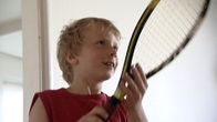 Nuori Emil Ruusuvuori pitelee tennismailaa edessään ja katsoo oikealle kamerasta.