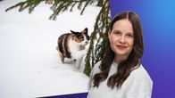 Laura Törnroos står framför en bild på en katt i snö som håller en tass mot en grankvist.