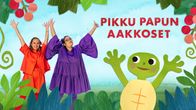 Heli Kajo ja Maiju Kopra pitävät käsiään yllä animaatiohahmokilpikonnan vasemmalla puolella.
