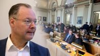 Janne Laineen kasvokuva, taustalle upotettu Savonlinnan valtuuston kokous.