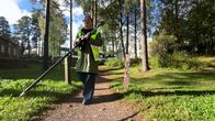 Nainen kävelee puistopolulla pitäen kädessään pitkää GPS-paikantimen vastaanotinantennia.