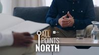 Man sitting in sofa facing another man with a notebook in his lap. A coffee table with a glass of water is seen between them.