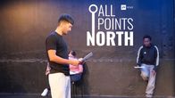 A man reads a paper with the All Points North logo in between. 