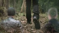 Henkilö kävelee metsäpolulla, joidenkin ihmishahmojen näkyessä utuisina hahmoina taustalla.