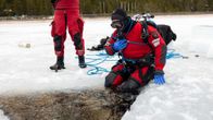 Janne Antola istuu sukelluspuku päällä avannon reunalla. 