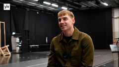 Mies vaaleissa lyhyissä hiuksissa istuu studiossa ja katsoo haastattelijaa. Miehellä on vihreä paitatakki. Taustalla oleva studio on tumma.