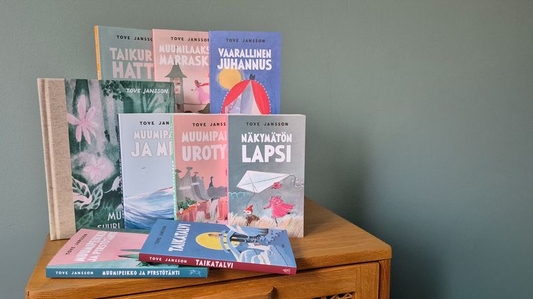 Kuvassa näkyy lipaston päällä kaikki yhdeksän muumiromaania.