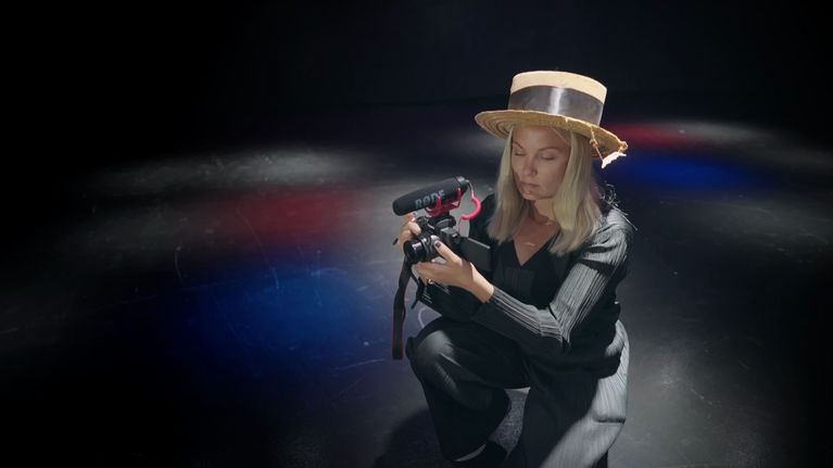 Elokuvaohjaaja Emilia Hernesniemi on polvistunut ja pitää kameraa käsissään. Hän katsoo kameran näyttöön.