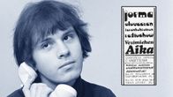 Toimittaja Jorma Elovaara puhelimen kuuloke poskellaan, upotuksena mainos Vesimiehen aika -kaseteista (kollaasi).