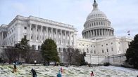 Ihmisiä laskee mäkeä Yhdysvaltain kongressin Capitol-rakennuksen lumisessa ympäristössä Washingtonissa.