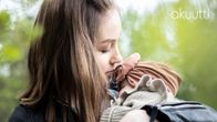Jonna Poutala pitää lähikuvassa kolmen kuukauden ikäistä Adessa-vauvaa sylissään. Taustalla vehreitä puita. 