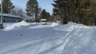 Matkailuauto ajaa lumisella Kuusamon Punaisentorintiellä.