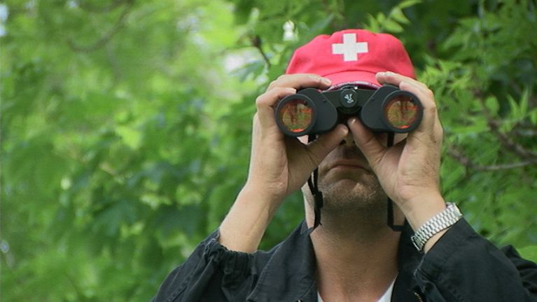Roman Schatz katsoo kiikareilla kameraan päin