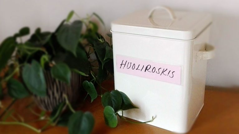 Pöydällä valkoinen huoliroskakori.