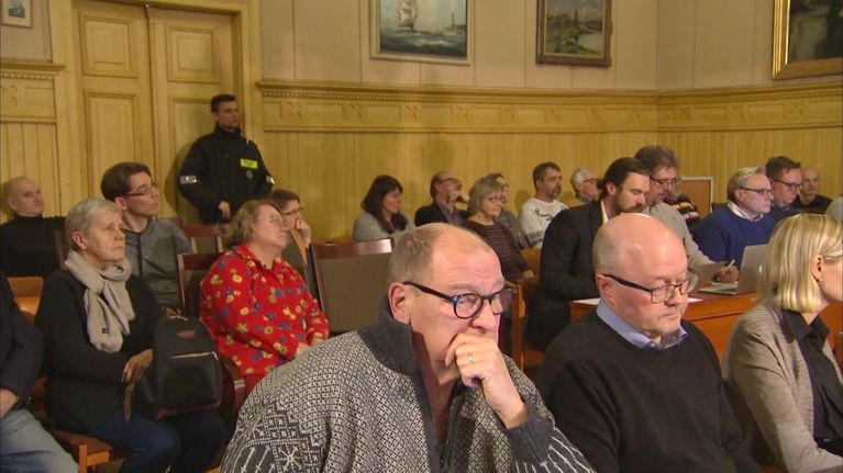Fullmäktigeledamoter på möte, i bakgrunden en väktare.