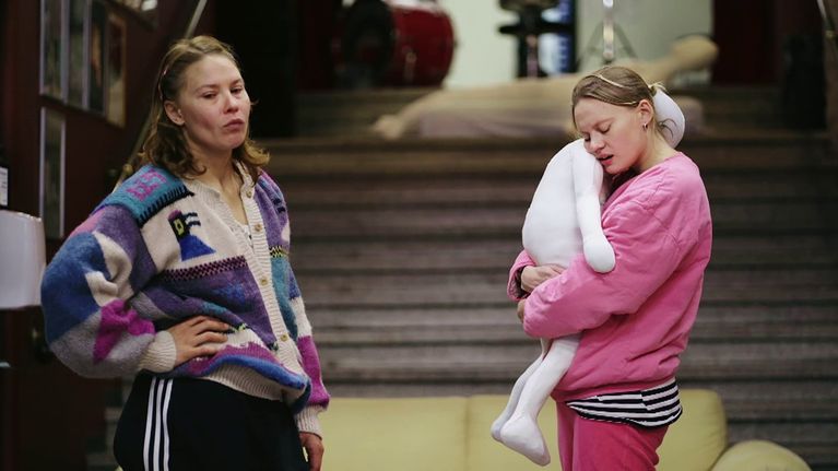 Seidi ja Ruusu Haarla seisovat portaikossa, Ruusu halaa lapsen oloista kangasnukkea ahdistuneen näköisenä. Kuvakaappaus ohjelmasta Luovia suhteita.