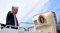 Donald Trump seisoo porrastasanteella Air Force One -lentokoneen oviaukon edustalla ja vilkuttaa.