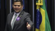 Harmaaseen pukuun pukeutunut mies näyttää peukaloa ylöspäin istuntosalissa. Vieressä näkyy Brasilian lippu.