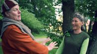 Yngve Källberg och Vivi-Anna Rehnström agerar mot varandra i sina teaterkläder i en grön park.