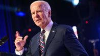 Yhdysvaltain presidentti Joe Biden pitää puhetta tummassa puvussa korokkeen takana, taustalla valonheitin.