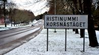 Vägskylt som det står Ristinummi Korsnäståget på. I bakgrunden kommer en bil körande. Det är lite snö på marken.
