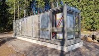 Kuvassa näkyy metsän reunaan rakennettu akkuvarastokontti, jossa on akkujen lisäksi akkujen lataamiseen ja purkamiseen liittyvää tekniikkaa. Akkuvarasto sijaitsee Savitaipaleella, Etelä-Karjalassa.  